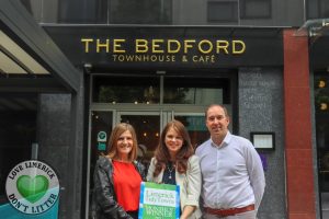 three people standing outside building holding sign